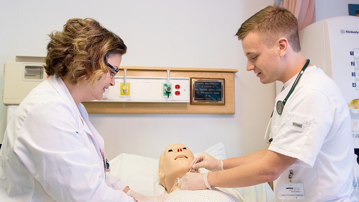 Nursing student with instructor practicing on a dummy